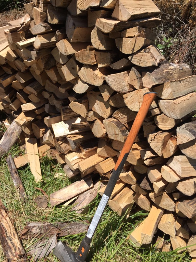 Splitting maul leaning against a stack of firewood